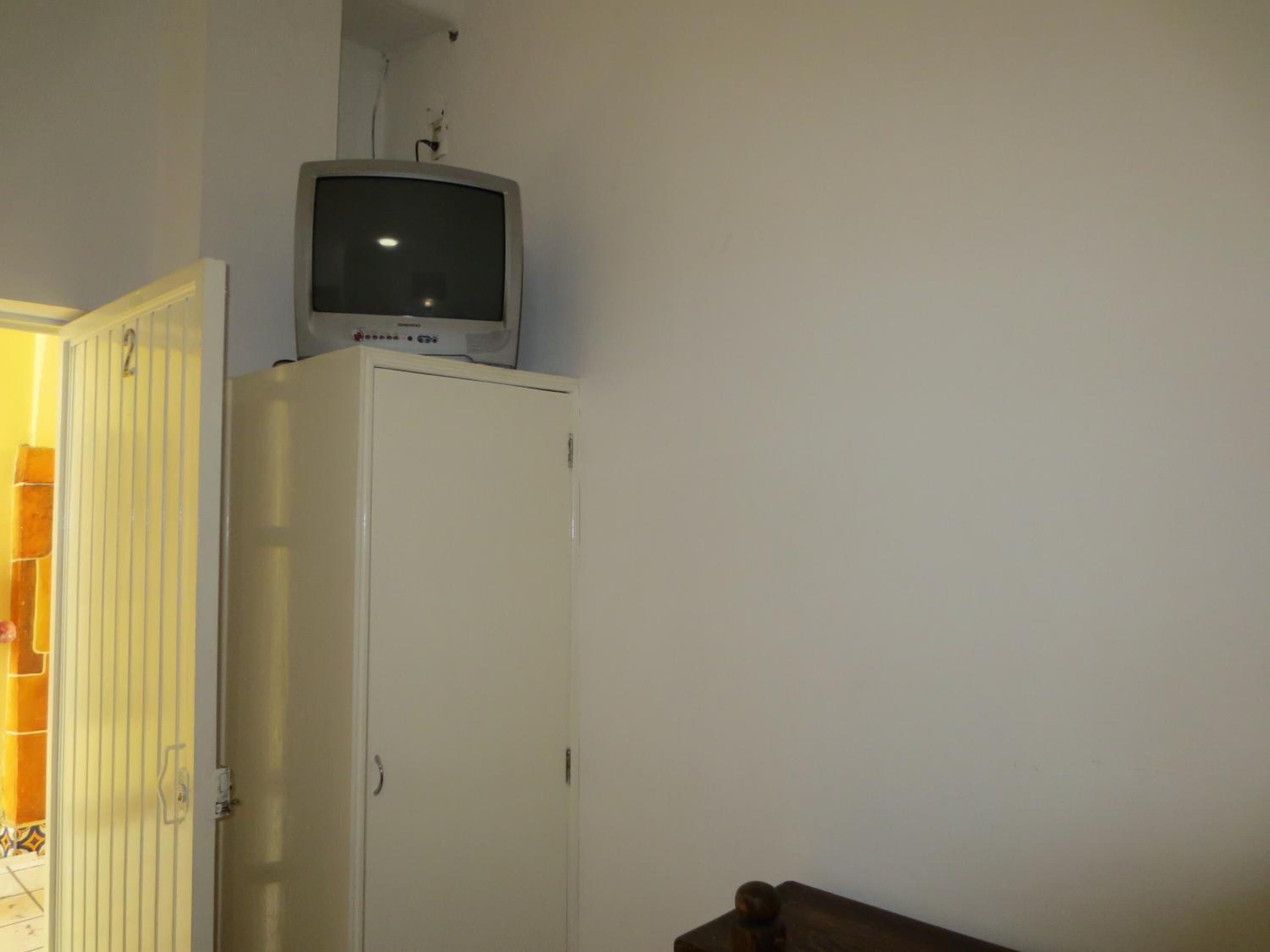 Um armário branco com uma televisão em cima.