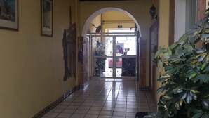 A hallway with tiled flooring, a large arched doorway, and a potted plant on the right. - Hotel Posada Diamante (Querétaro)