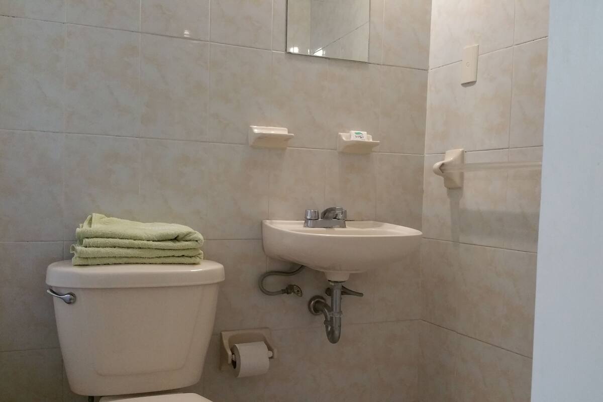 A bathroom with a toilet, sink, and towel stack.