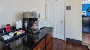 Una cocina con cafetera, tazas y microondas.