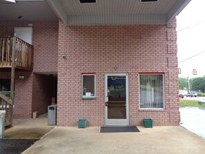 Un edificio de ladrillo con una escalera de madera, una puerta y dos ventanas.