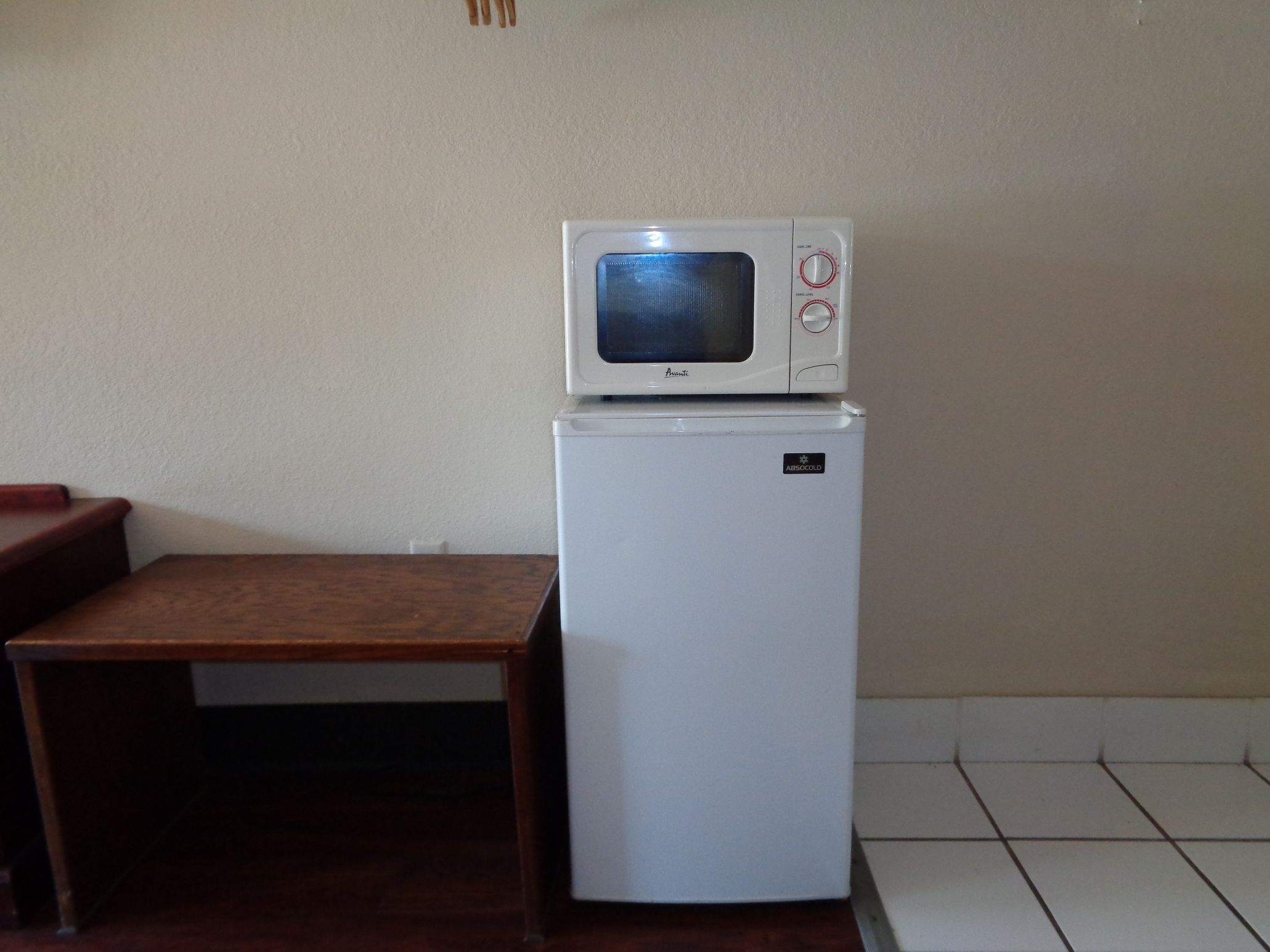 Une petite cuisine équipée avec un micro-ondes et un réfrigérateur blancs.