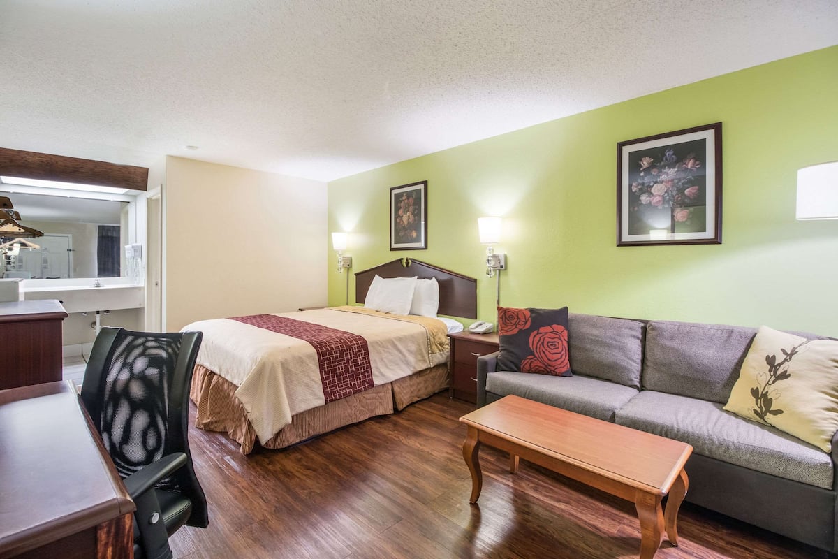 Quarto de hotel com cama, sofá, escrivaninha e cadeira.