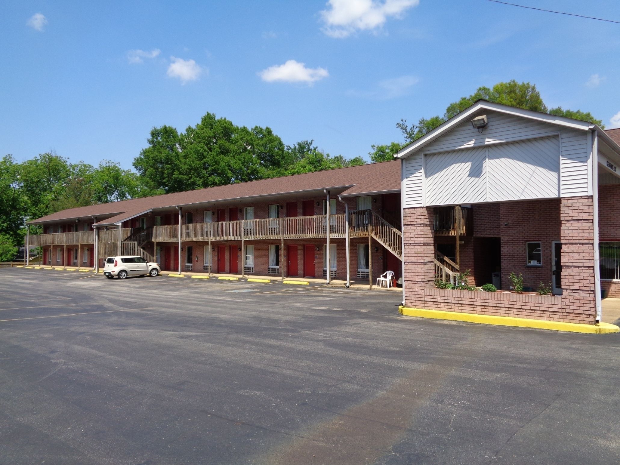 A motel with multiple rooms, a covered parking area, and a small outdoor seating area.