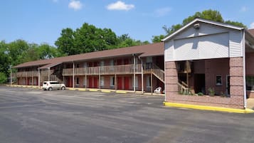 A motel with multiple rooms, a covered parking area, and a small outdoor seating area.