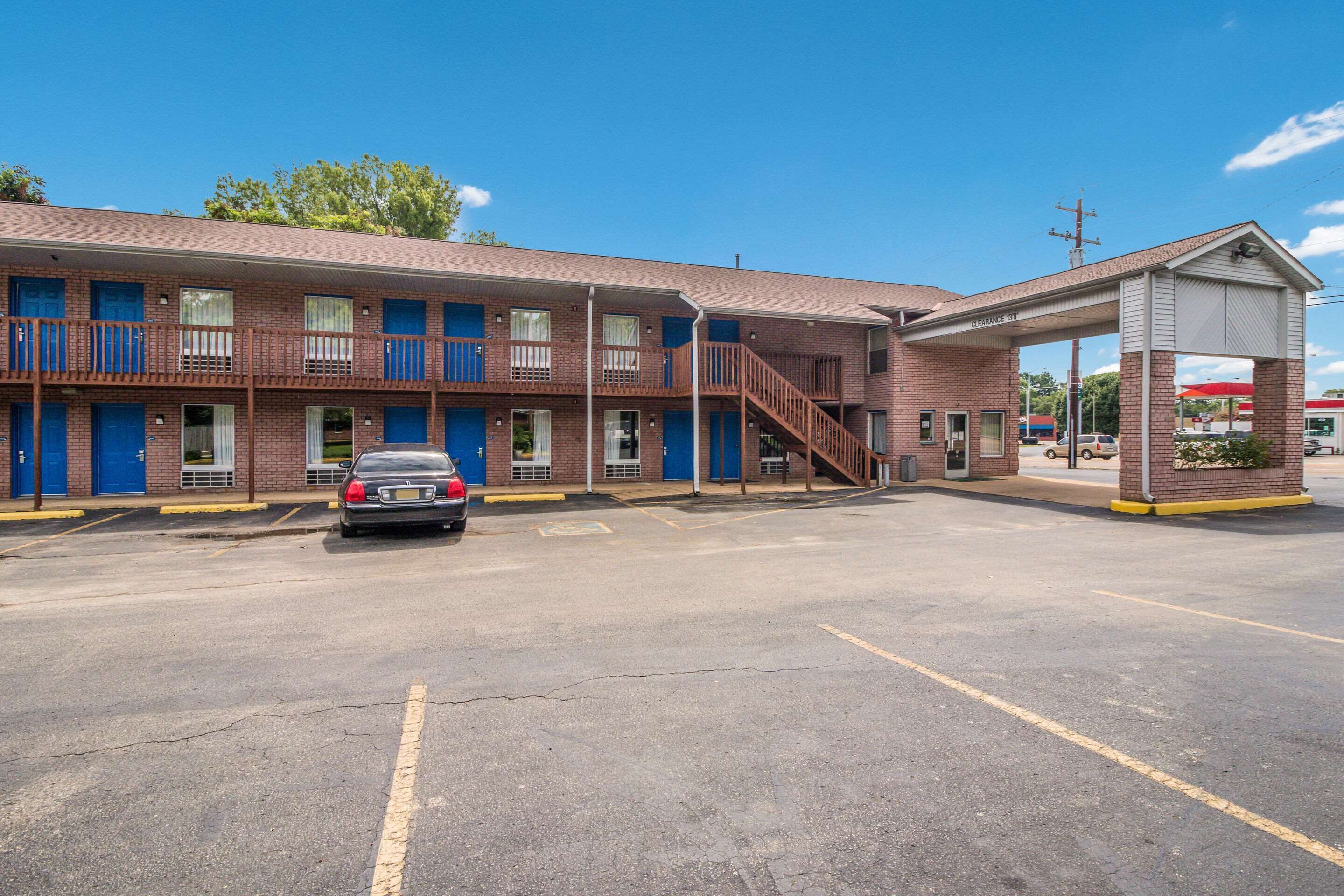 A multi-story motel with a parking lot, a gas station, and a covered walkway.