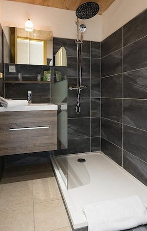 Een moderne badkamer met een douche, een glazen badkuip en een wastafel met spiegel.