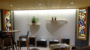 A cozy room with a wooden ceiling, a round table with chairs, a sofa, and a small bookshelf. - Hotel du Midi (Thones)