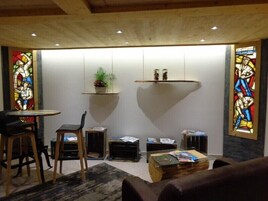Una habitación acogedora con techo de madera, una mesa redonda con sillas, un sofá y una pequeña estantería.