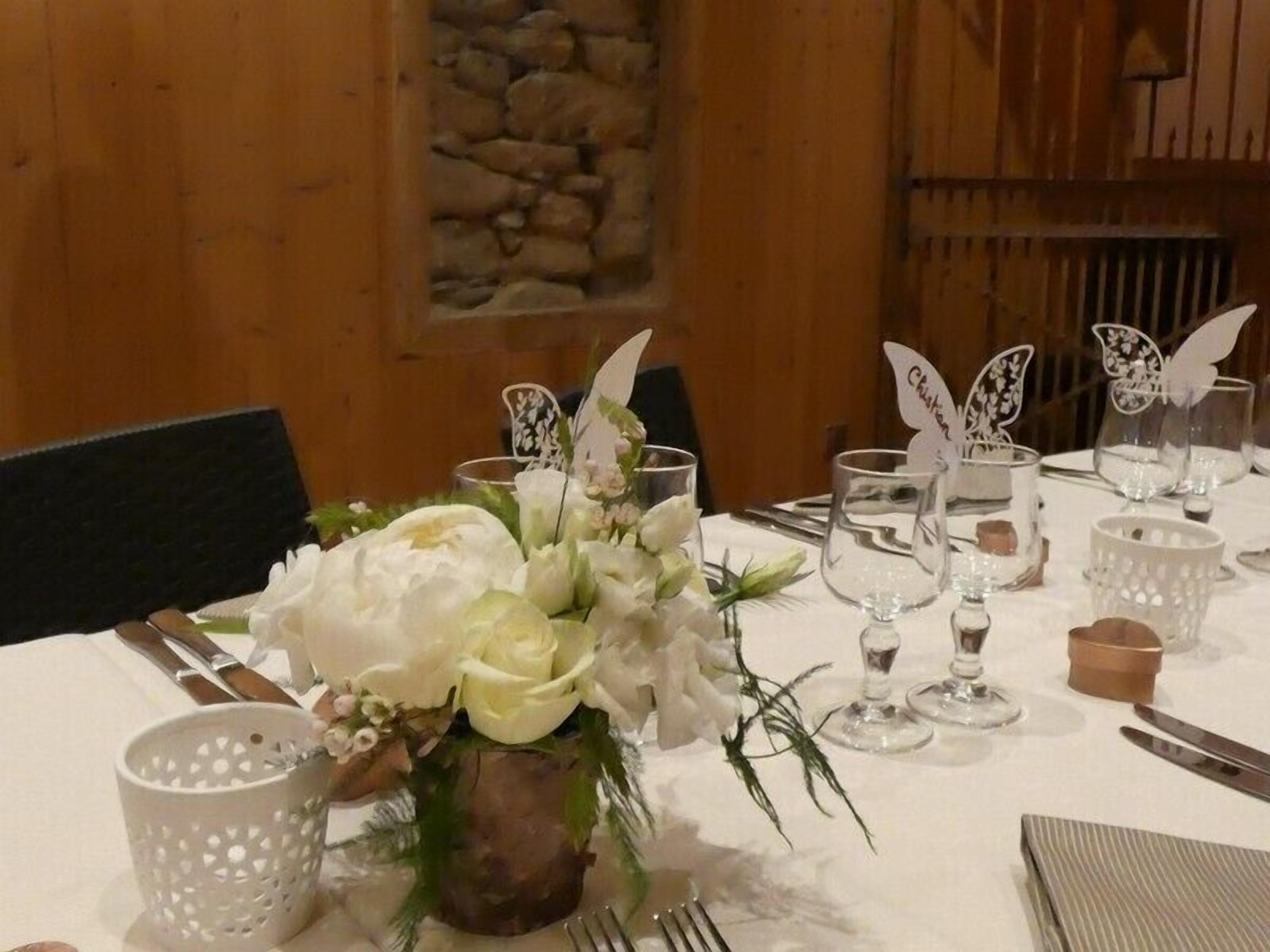 A table set with white flowers, clear glassware, and butterfly-shaped centerpieces.