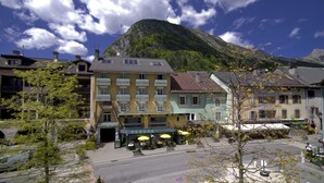 A hotel with outdoor seating and a mountain backdrop. - Hotel du Midi (Thones)