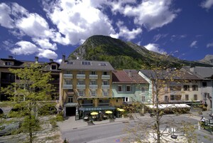 Hotel con terraza al aire libre y montañas al fondo.