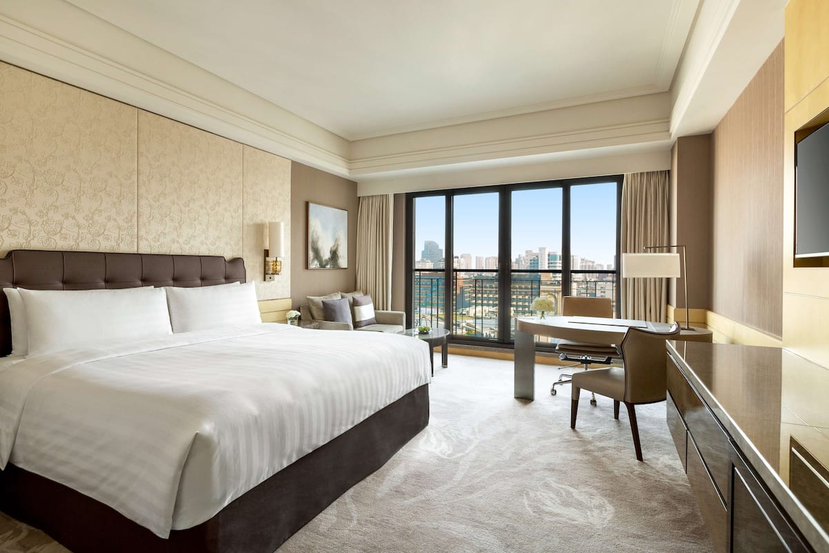 Ein geräumiges Hotelzimmer mit einem großen Bett, einem Schreibtisch und Blick auf die Stadt.