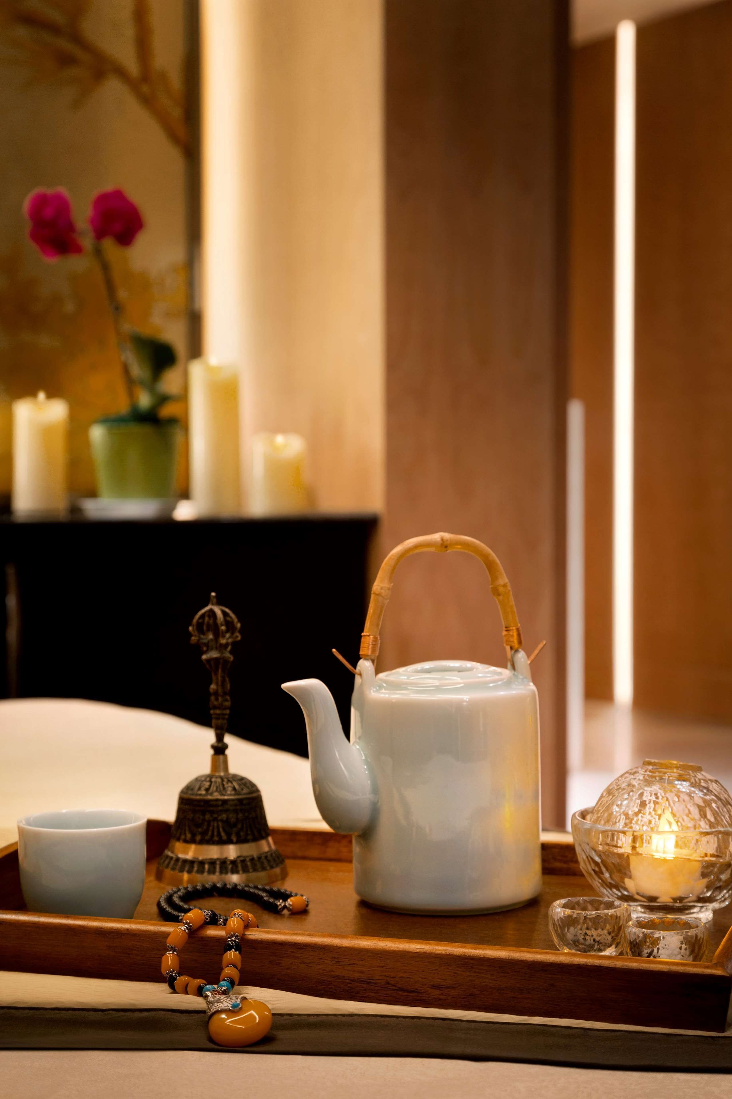 A tray with a teapot, a bell, a candle, and a glass bowl with a candle inside.