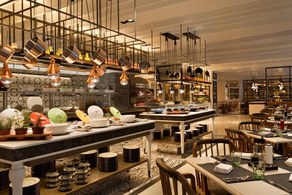 Un restaurante moderno con una isla central, varias lámparas colgantes y una variedad de platos expuestos en estanterías.