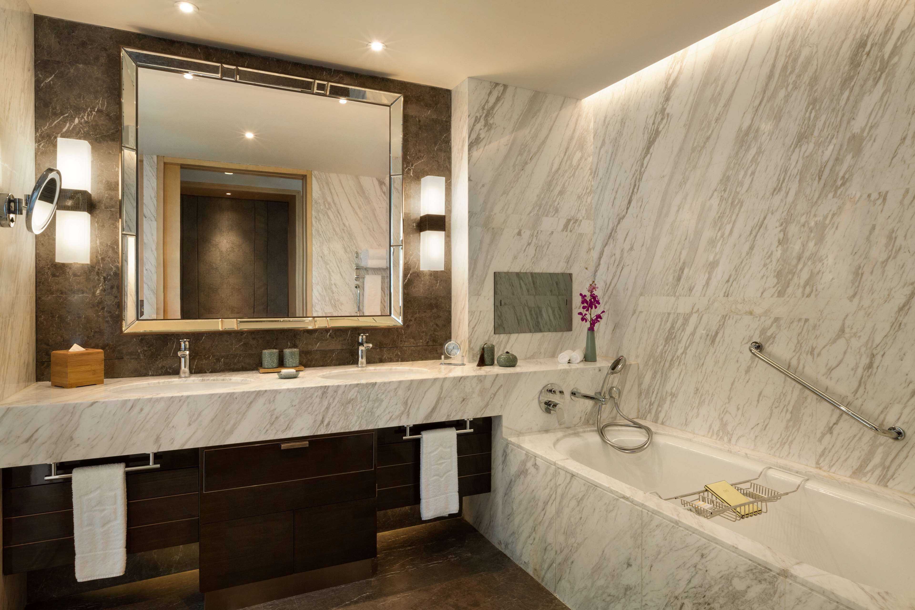 Un baño moderno con tocador de mármol, un espejo grande, bañera y zona de ducha.