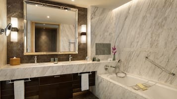 Un baño moderno con tocador de mármol, un espejo grande, bañera y zona de ducha.