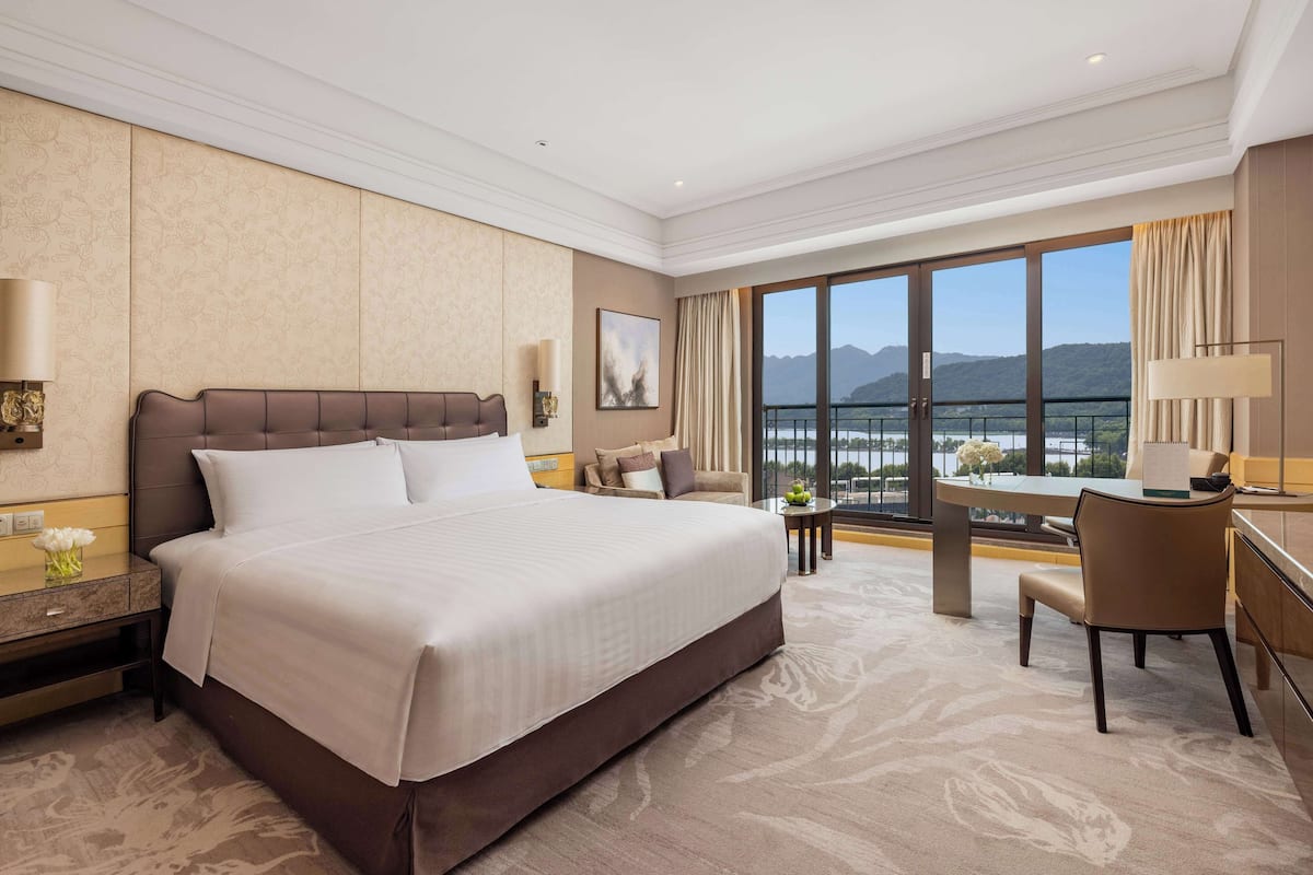 Ein Hotelzimmer mit einem großen Bett, einem Schreibtisch und Bergblick durch die Fenster.