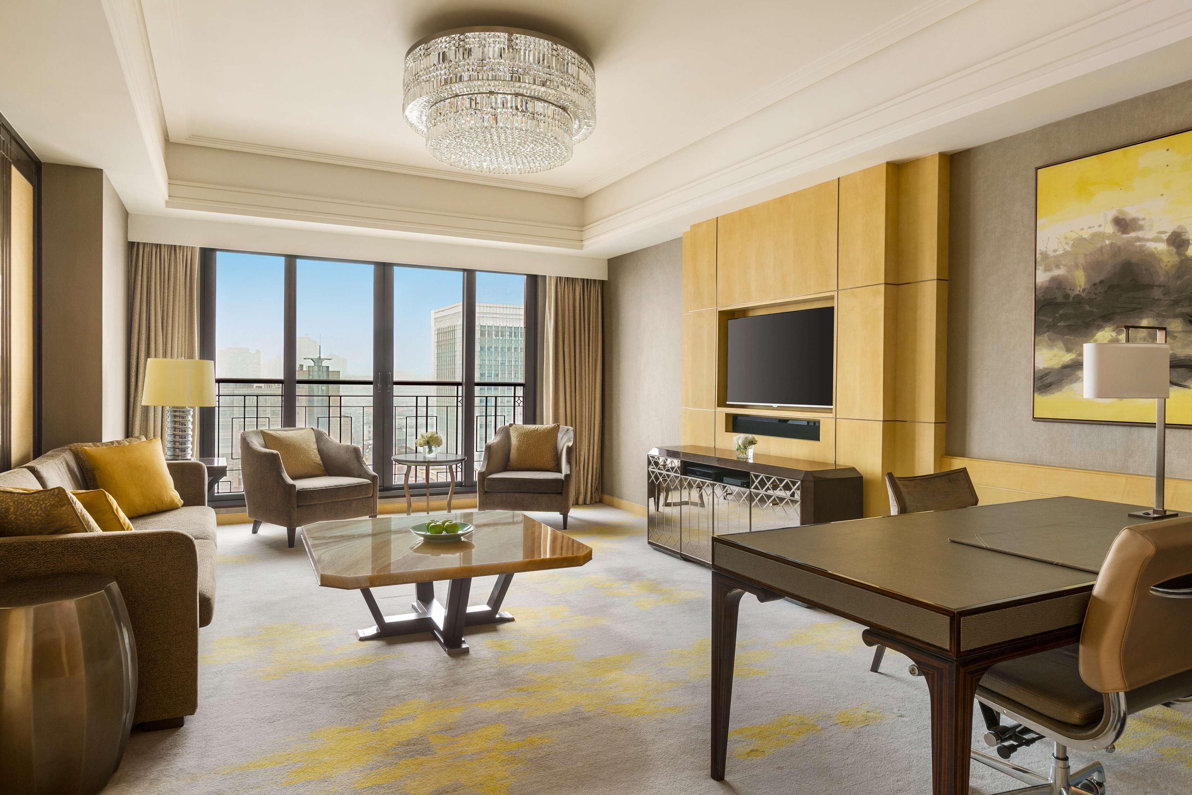Ruime hotelkamer met een groot balkon, een eethoek en een zithoek met televisie en kunstwerken.