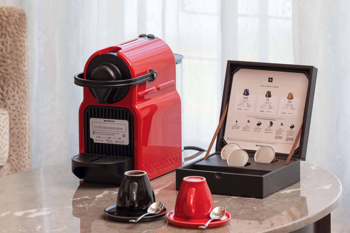Eine Nespresso-Kaffeemaschine, eine Kaffeetasse und eine Auswahl an Nespresso-Kapseln auf einer Marmortischplatte.