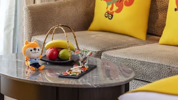 A round table with a plush toy, a fruit basket, and a tray of snacks.