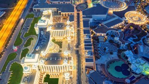 An aerial view of a large, well-lit hotel with multiple domed structures, a central courtyard, and a landscaped pool area. - The Land Of Legends Kingdom Hotel (Serik)