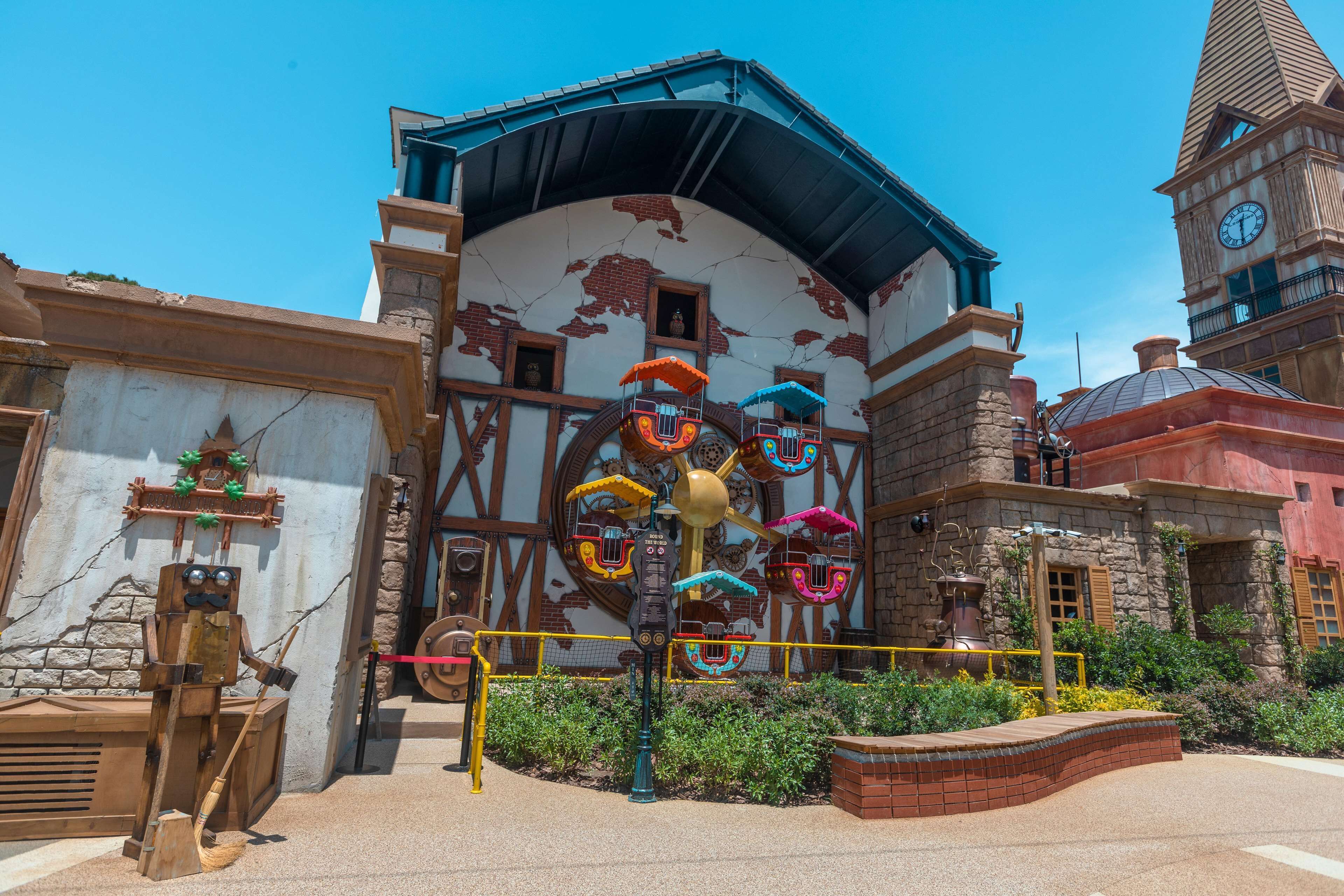Un bâtiment doté d’une tour horlogée, d’un carrousel et d’une statue de robot en bois.