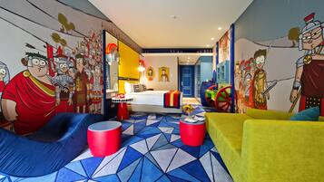 A modern, colorful room with a geometric patterned floor, a bed with a colorful headboard, and a wall mural depicting animated characters.