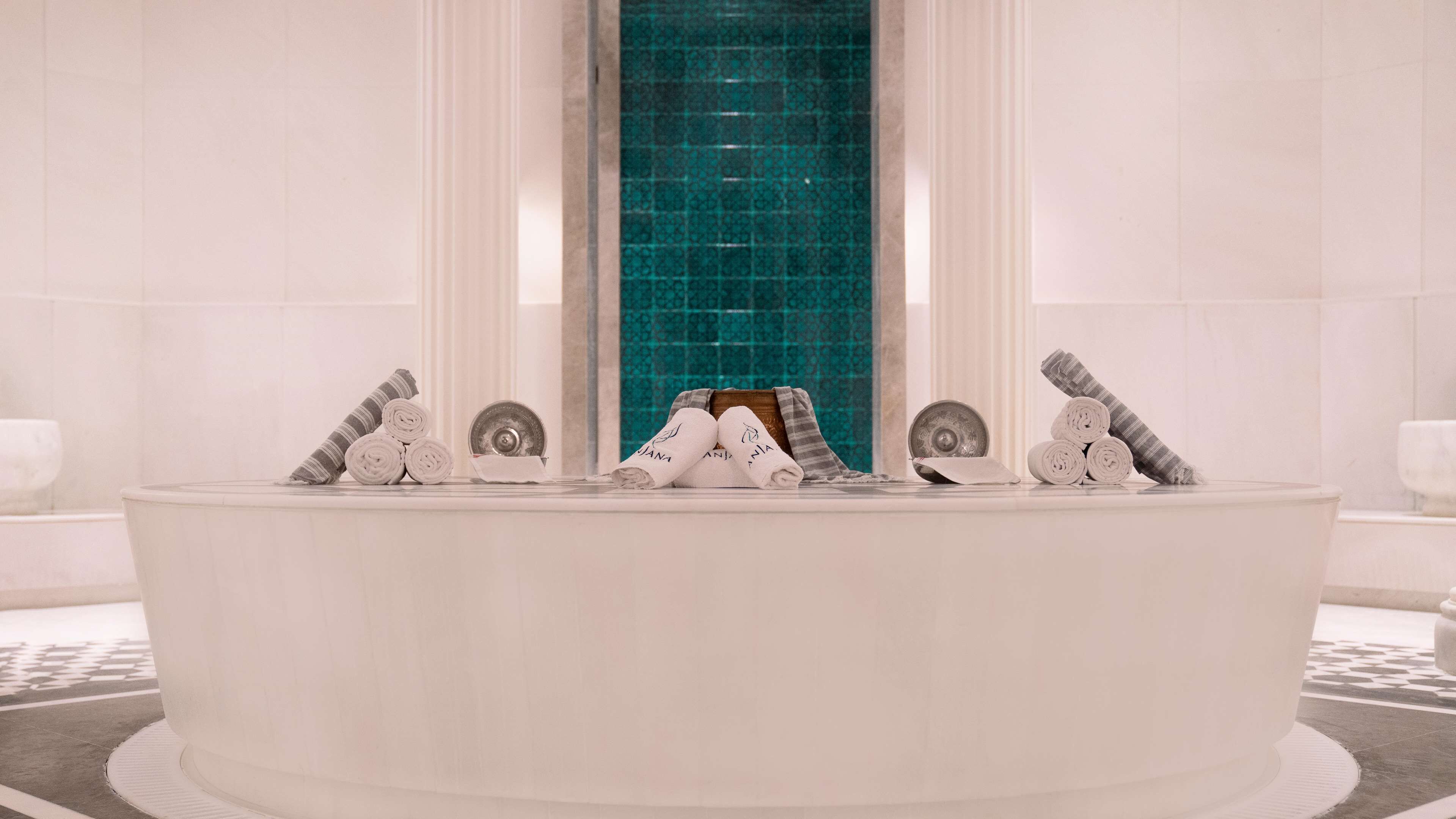 Une grande baignoire de forme ovale, avec des serviettes enroulées et un objet décoratif placé au centre.