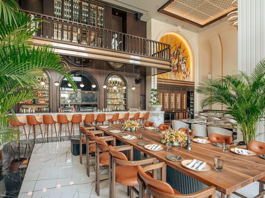 A spacious dining area with a long wooden table set for a meal, surrounded by numerous chairs.