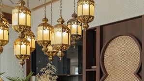 Montaje de bufé con diversos alimentos y bebidas, faroles decorativos colgantes y una pared de estilo tradicional al fondo.