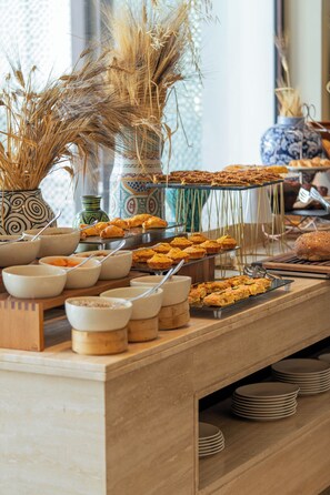 Une table de buffet avec divers plats et des bols, un vase contenant des plantes séchées et un vase bleu et blanc à motifs.