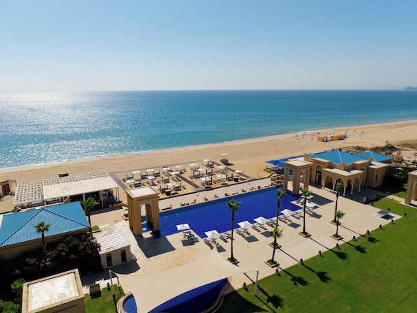 Un resort con piscina, playa y cielo azul despejado.
