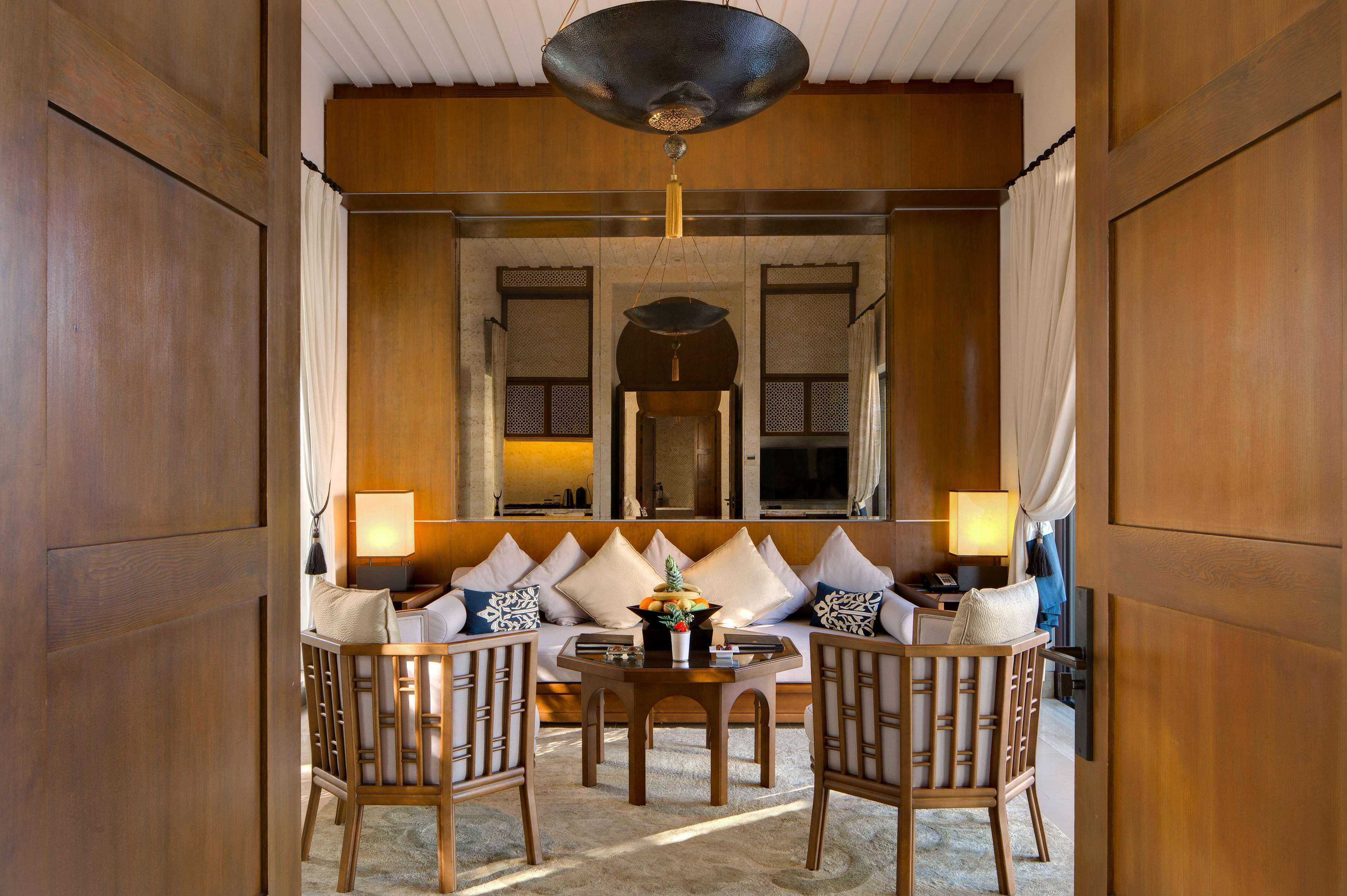 A traditional room with a sofa set, two chairs, a table, and a hanging light fixture.