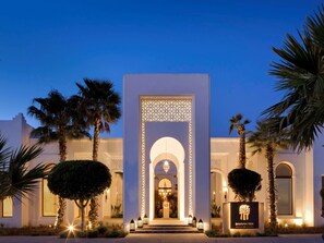 A hotel entrance with a decorative archway, palm trees, and a sign for Banyatree Spa & Fitness. - Banyan Tree Tamouda Bay (Allyene)