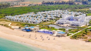 Vista aérea de un complejo turístico costero con varias villas, una playa y una zona de piscina.