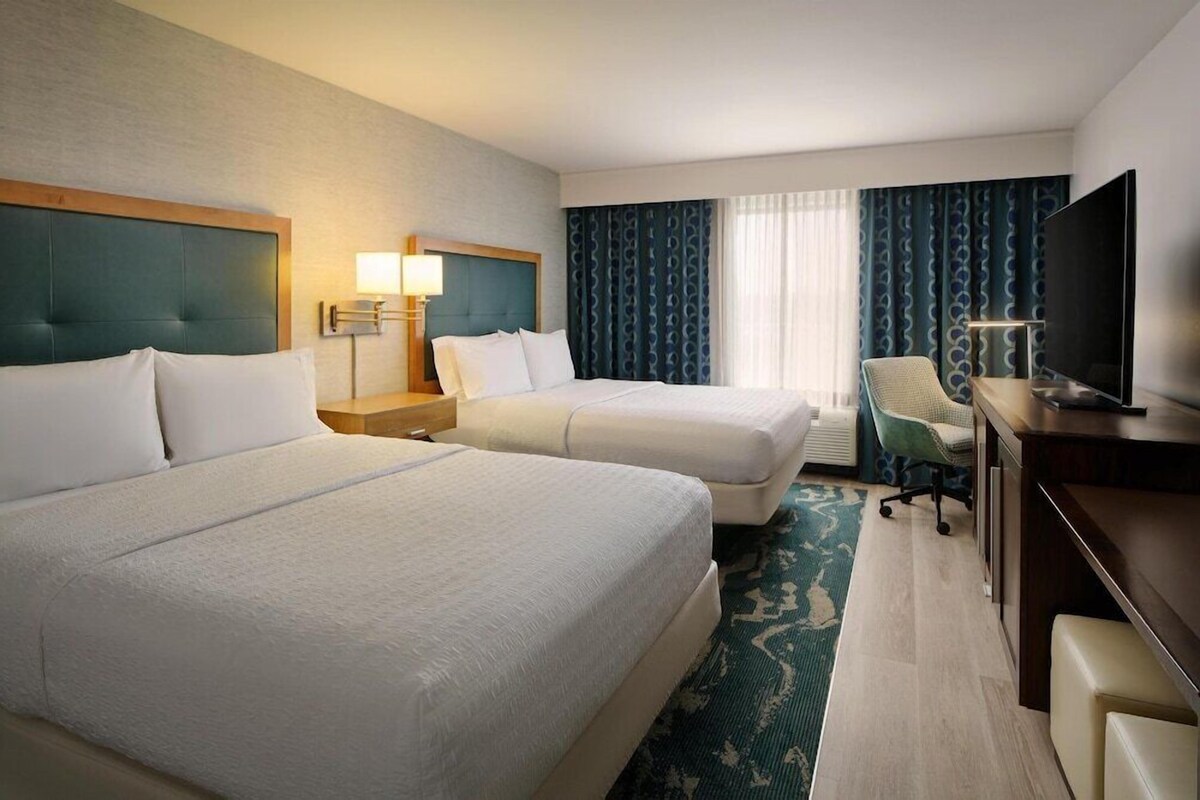Een hotelkamer met twee bedden, een bureau, een televisie en een stoel.