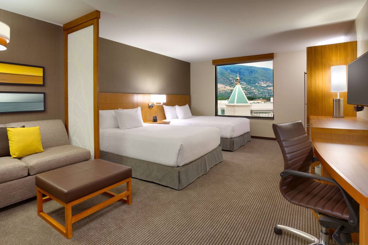 Une chambre d’hôtel avec deux lits, un canapé, un bureau et une vue sur les montagnes.