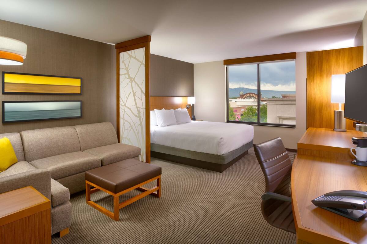 Une chambre d’hôtel avec un lit, un canapé, un bureau et une vue sur la ville.