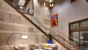 A spacious lobby with a staircase, seating area, and a large window.