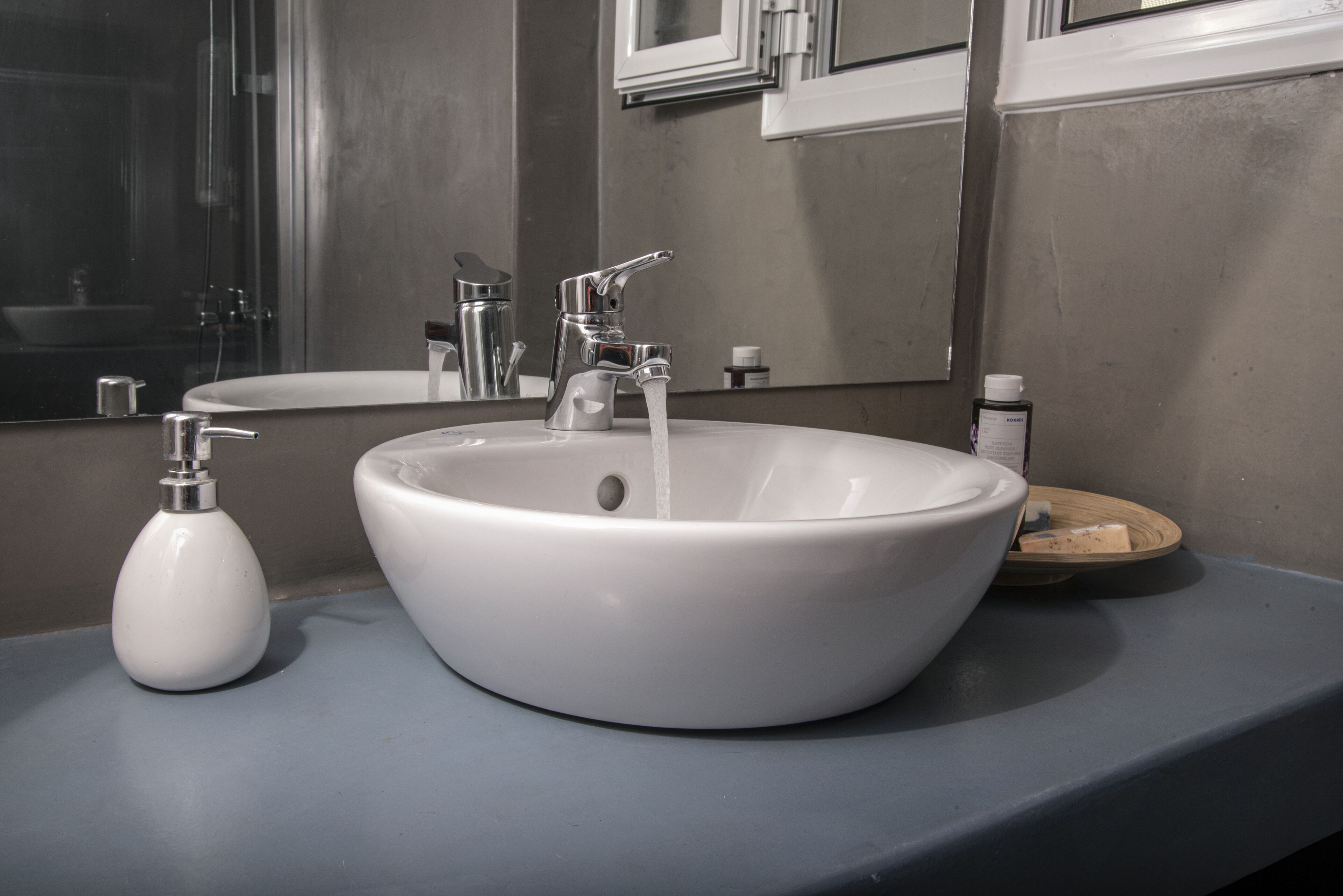 A bathroom with a white sink, a faucet, and a soap dispenser.