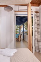 Un dormitorio con una cama, vistas a un balcón con mesa y sillas, y una estructura de techo de madera.