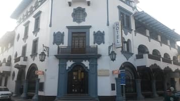 Ein Gebäude im Kolonialstil mit einem zentralen Eingang, Balkonen und einem Schild, das es als Hotel kennzeichnet.