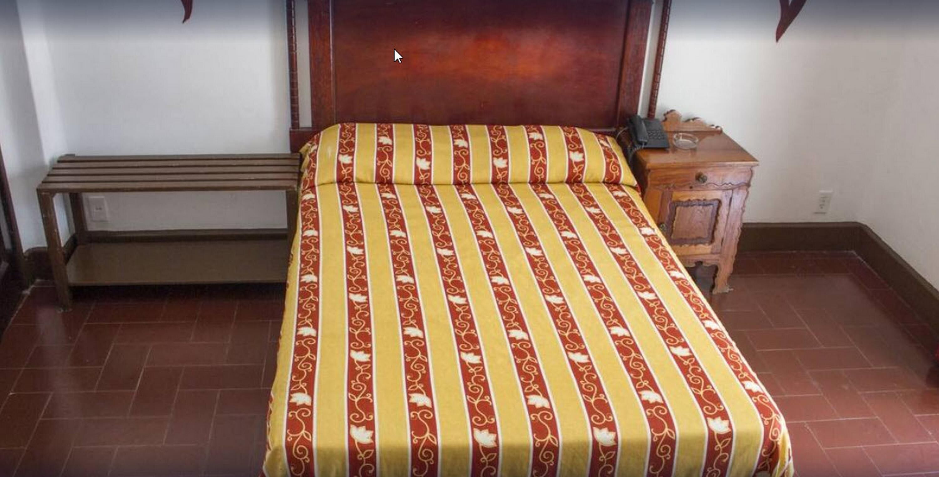 Un dormitorio con una cama, una mesita de noche y un banco.