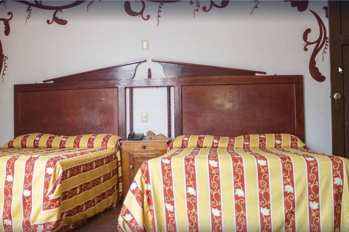 Habitación doble con dos camas, cada una con colcha a rayas.