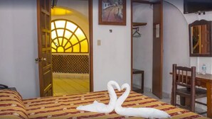 A hotel room with a bed, a desk, a chair, a TV, and a door leading to a balcony. - Hotel Colonial (Manzanillo)