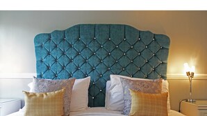 A bed with a tufted headboard, multiple pillows, and a bedside lamp. - The Millbrook B & B (Torquay)