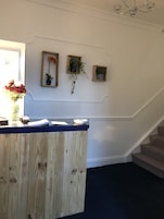 A reception desk with a wooden finish, a small potted plant, and a framed picture on the wall.