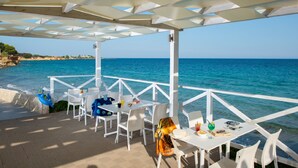 An outdoor terrace with white tables and chairs, overlooking a clear blue sea. - Hotel President Sea Palace (Noto)