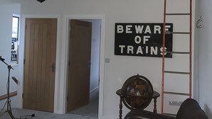 A loft-style room with a wooden staircase, a mounted deer head, a warning sign about trains, a vintage globe, and a leather sofa. - The Redan (Radstock)